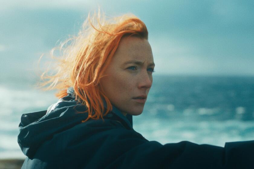 A woman with red hair looks over the sea.