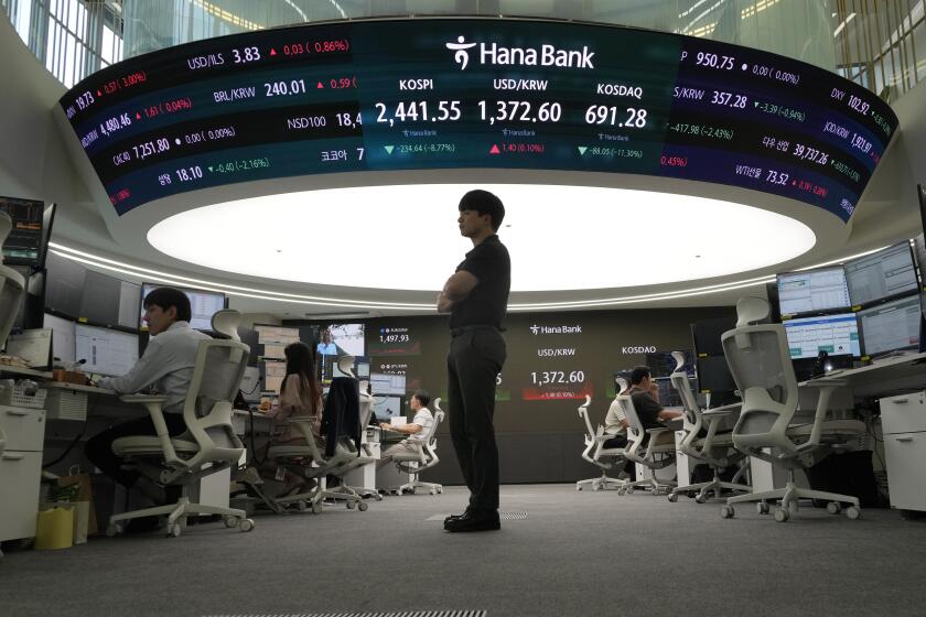 Currency trader work stands near a screen showing the Korea Composite Stock Price Index (KOSPI), top center left, and and the foreign exchange rate between U.S. dollar and South Korean won, top center, at the foreign exchange dealing room of the KEB Hana Bank headquarters in Seoul, South Korea, Monday, Aug. 5, 2024. (AP Photo/Ahn Young-joon)