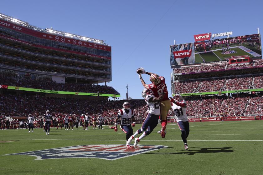 San Francisco 49ers tight end George Kittle (85) catches a touchdown pass between New England Patriots safety Dell Pettus, middle left, and cornerback Jonathan Jones (31), as cornerback Marcus Jones (25) watches, during the first half of an NFL football game in Santa Clara, Calif., Sunday, Sept. 29, 2024. (AP Photo/Jed Jacobsohn)