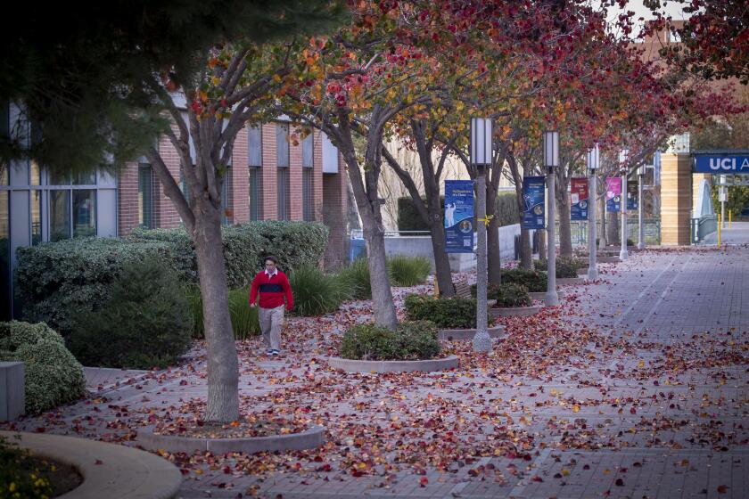 Irvine, CA - January 07: A person walks down a campus path amidst a mostly empty University of California-Irvine campus Friday, Jan. 7, 2022. The University of California officials announced the extension of remote instruction on five campuses, stating the high coronavirus positivity rates call for extra precautions at UC campuses. (Allen J. Schaben / Los Angeles Times)