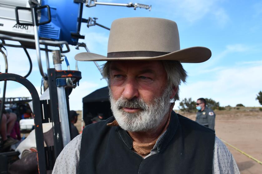 Alec Baldwin wearing a cowboy hat and vest on a film set in the desert