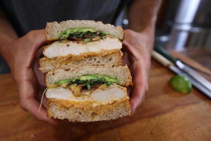 VENICE, CA - AUGUST 28, 2024 - Food content creator Owen Han, known as the "Sandwich King," holds his completed OG Spicy Chicken Sandwich in his studio, kitchen in Venice on August 28, 2024. Han is known for sharing creative sandwich recipes with his TikTok, YouTube and Instagram followers. Han started making videos in his apartment while attending USC. He has over 4 million followers. He is the author of the book, "Stacked - the art of the perfect sandwich." (Genaro Molina/Los Angeles Times)