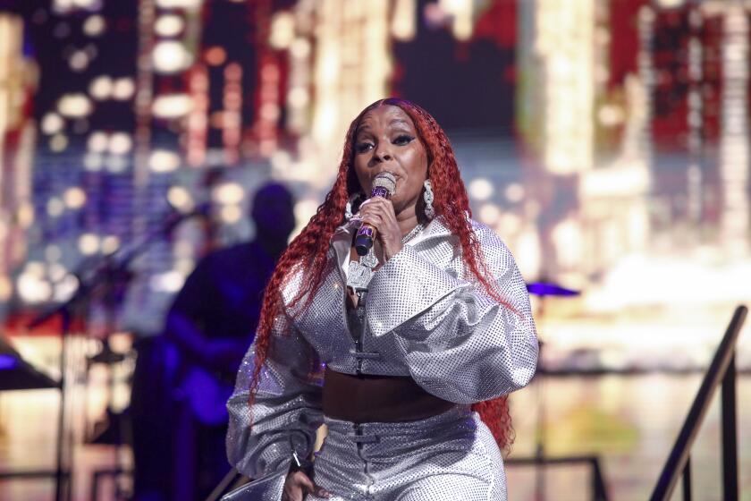 Mary J. Blige singing into a microphone onstage during a concert