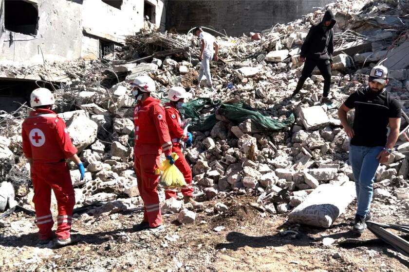 People along with rescue workers examine damage from an Israeli strike 