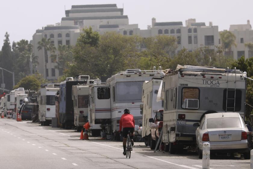 MARINA DEL REY, CA - MAY 24, 2022 - - A bicyclist rides past a line of campers that make up the Balloon Creek homeless encampment along Jefferson Boulevard in Marina Del Rey on May 24, 2023. A new LAPD report links RV encampments with increased crime in the surrounding areas and mentions the Ballona Creek encampment as problematic. (Genaro Molina / Los Angeles Times)