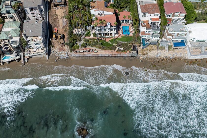 Malibu, CA - September 11: A beachfront home at 31430 Broad Beach Rd., center, has an empty lot next door, with an excavator parked on it on Wednesday, Sept. 11, 2024 in Malibu, CA. (Brian van der Brug / Los Angeles Times)