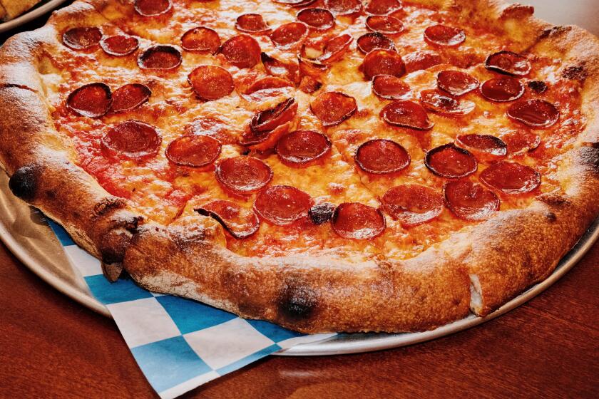 A closeup of a pepperoni pizza on blue-and-white checkered paper at LaSorted's pizzeria in Chinatown