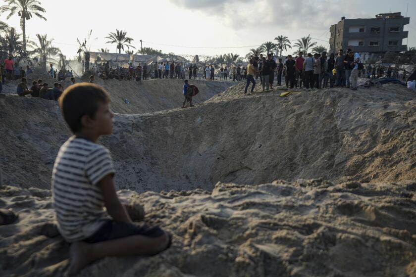 Palestinians look at the destruction after an Israeli airstrike on a crowded tent camp housing Palestinians displaced by the war in Muwasi, Gaza Strip, Tuesday, Sept. 10, 2024. (AP Photo/Abdel Kareem Hana)